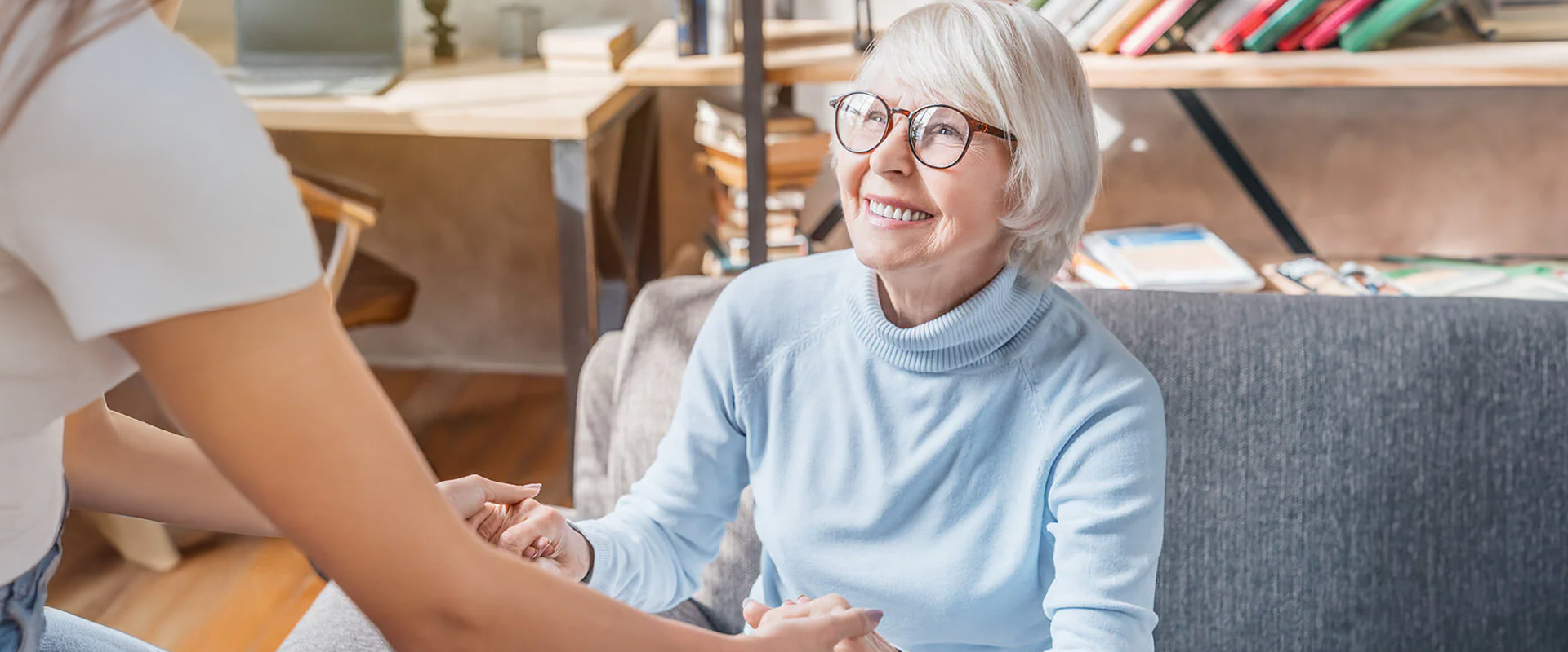 Smiling elderly woman interacting with a caregiver in a cozy room.